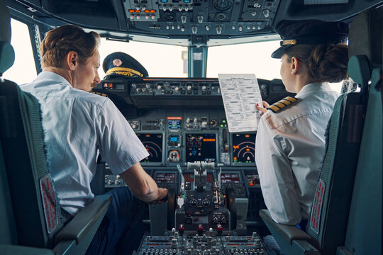 Two pilots in a flight deck reviewing paperwork before departure